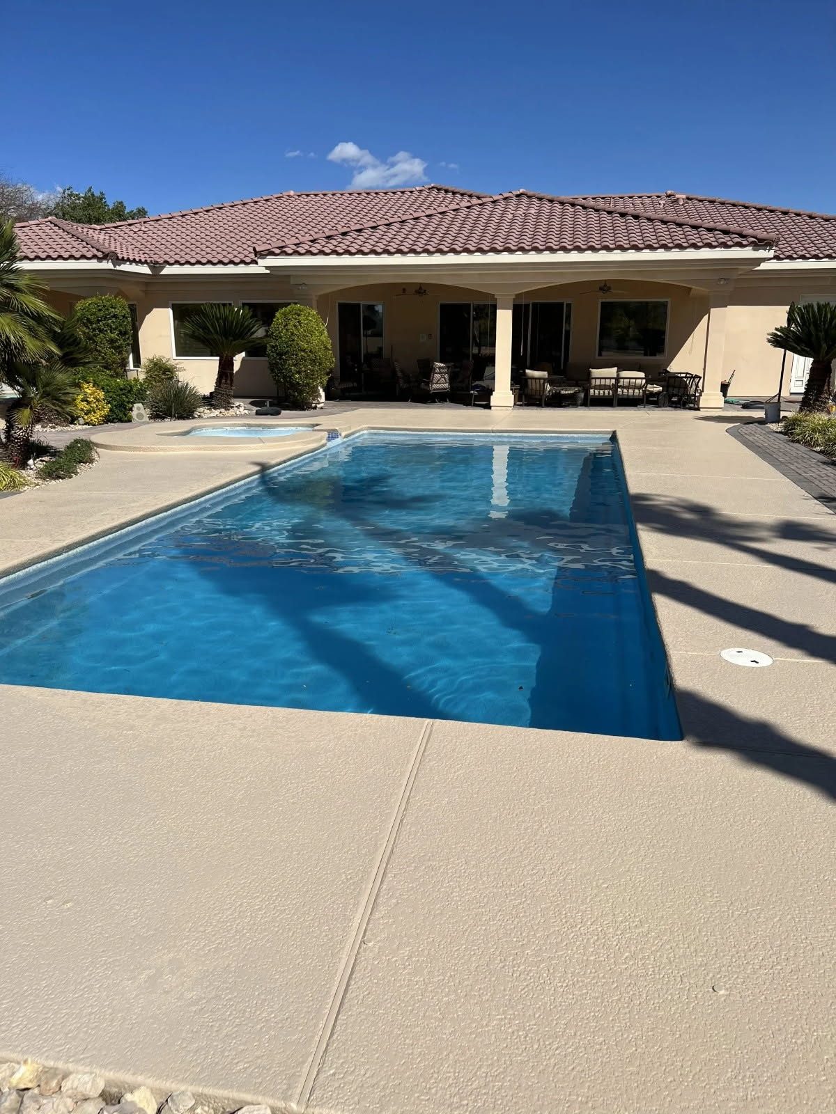 Resurfaced sand-toned deck around a rectangular blue pool